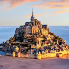 Bajkowy zamek na wodzie we Francji, Mont Saint-Michel, w blasku zachodzącego słońca, otoczony wodami oceanu.