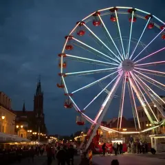 Podświetlany diabelski młyn na Rynku Kościuszki w Białymstoku, wieczorem, z widokiem na kamienice i kościół.