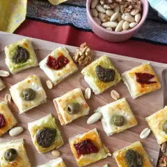 Pyszne przekąski francuskie z oliwkami, pesto i suszonymi pomidorami, ułożone na desce.