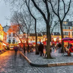 Wieczorny spacer po wzgórzu Montmartre. Brukowana ulica, kawiarnie, artyści malujący na placu.