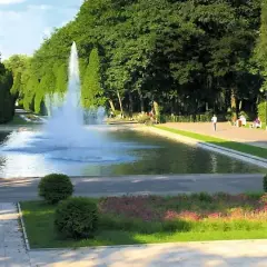 Park z fontanną i geometrycznie przyciętymi drzewami, przypominający ogrody w stylu Versailles.