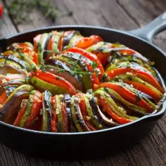 Ratatouille w naczyniu żeliwnym, idealne danie, by dowiedzieć się, co zjeść we Francji. Aromatyczne warzywa zapiekane z ziołami.