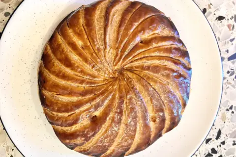 Złocista galette des rois, pieczona do perfekcji, czeka na odkrycie ukrytej w niej figurki.