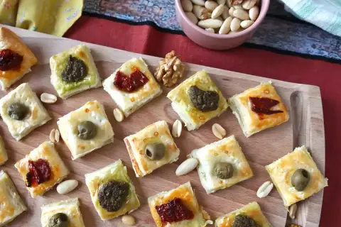 Pyszne przekąski francuskie z oliwkami, pesto i suszonymi pomidorami, ułożone na desce.