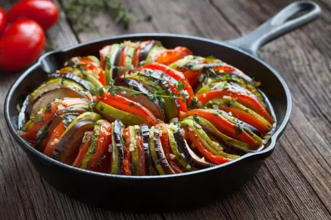 Ratatouille w naczyniu żeliwnym, idealne danie, by dowiedzieć się, co zjeść we Francji. Aromatyczne warzywa zapiekane z ziołami.