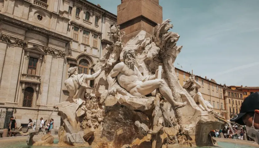 Fontanna Czterech Rzek na Piazza Navona w Rzymie, z majestatycznymi rzeźbami i turystami w tle.