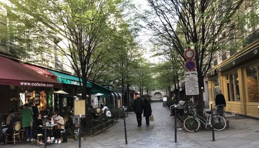 Spacerem w paryskiej dzielnicy Le Marais, z kawiarniami i sklepami po bokach, wczesną wiosną.