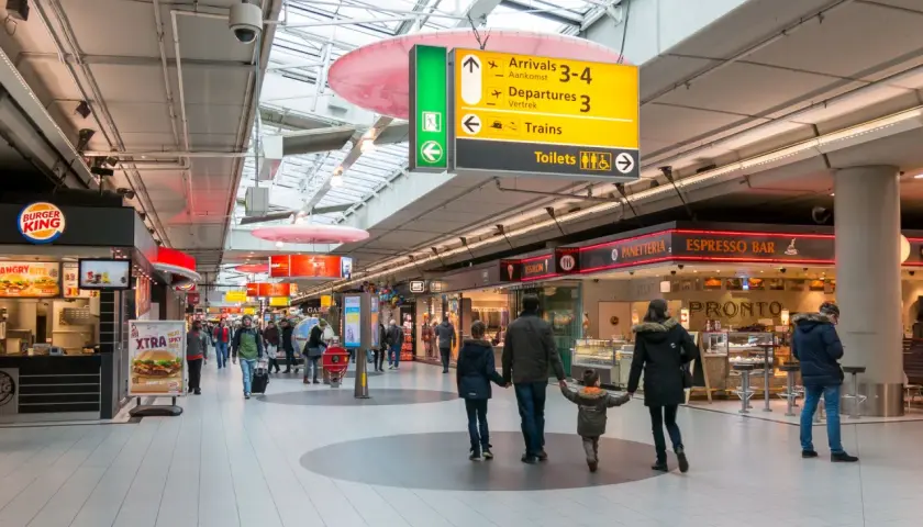 Lotnisko w Amsterdamie: rodzina idzie przez terminal, obok Burger Kinga i sklepów.
