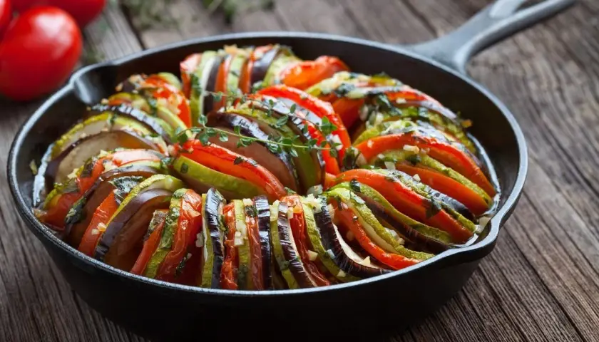 Ratatouille w naczyniu żeliwnym, idealne danie, by dowiedzieć się, co zjeść we Francji. Aromatyczne warzywa zapiekane z ziołami.