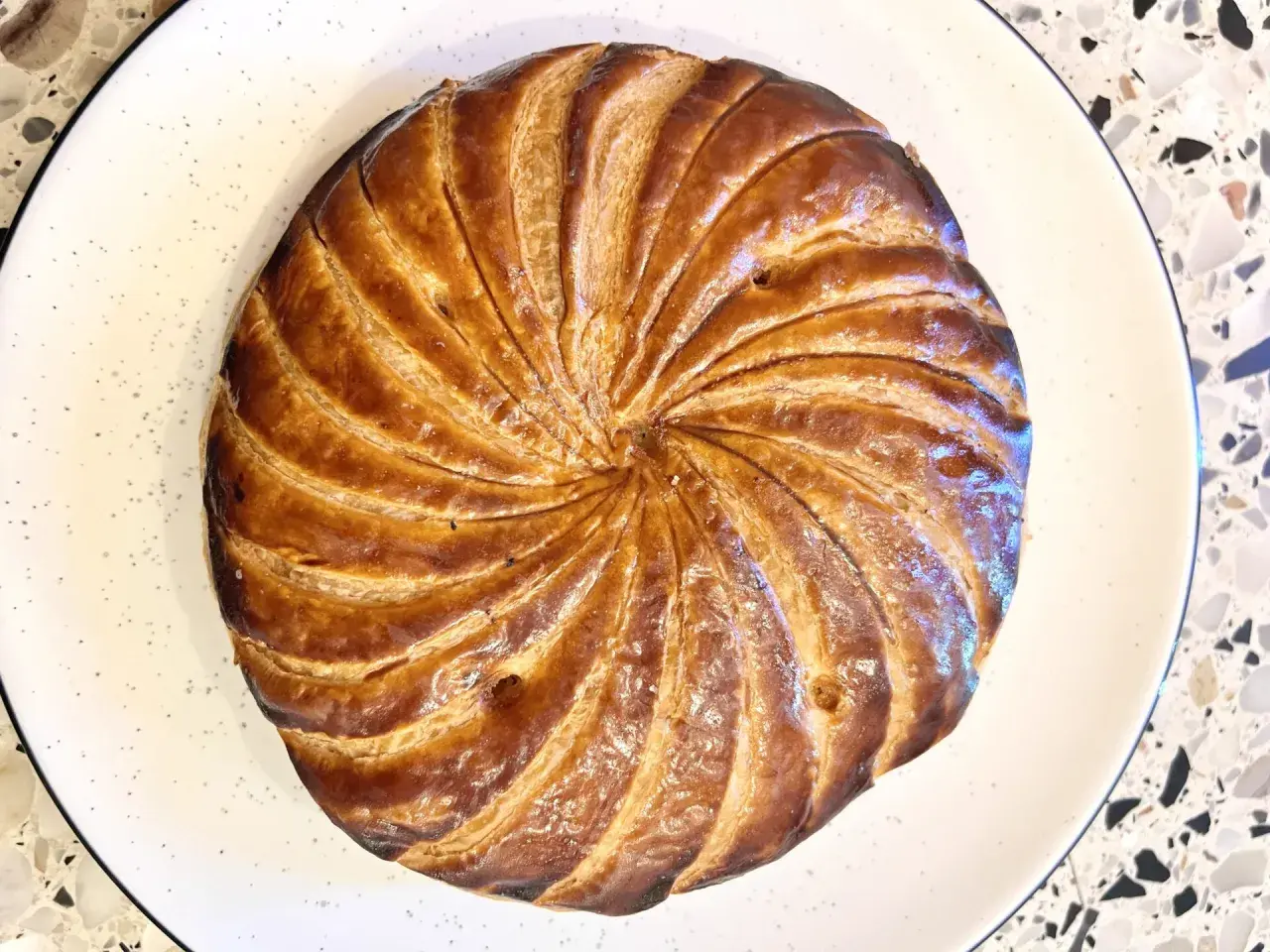 Złocista galette des rois, pieczona do perfekcji, czeka na odkrycie ukrytej w niej figurki.
