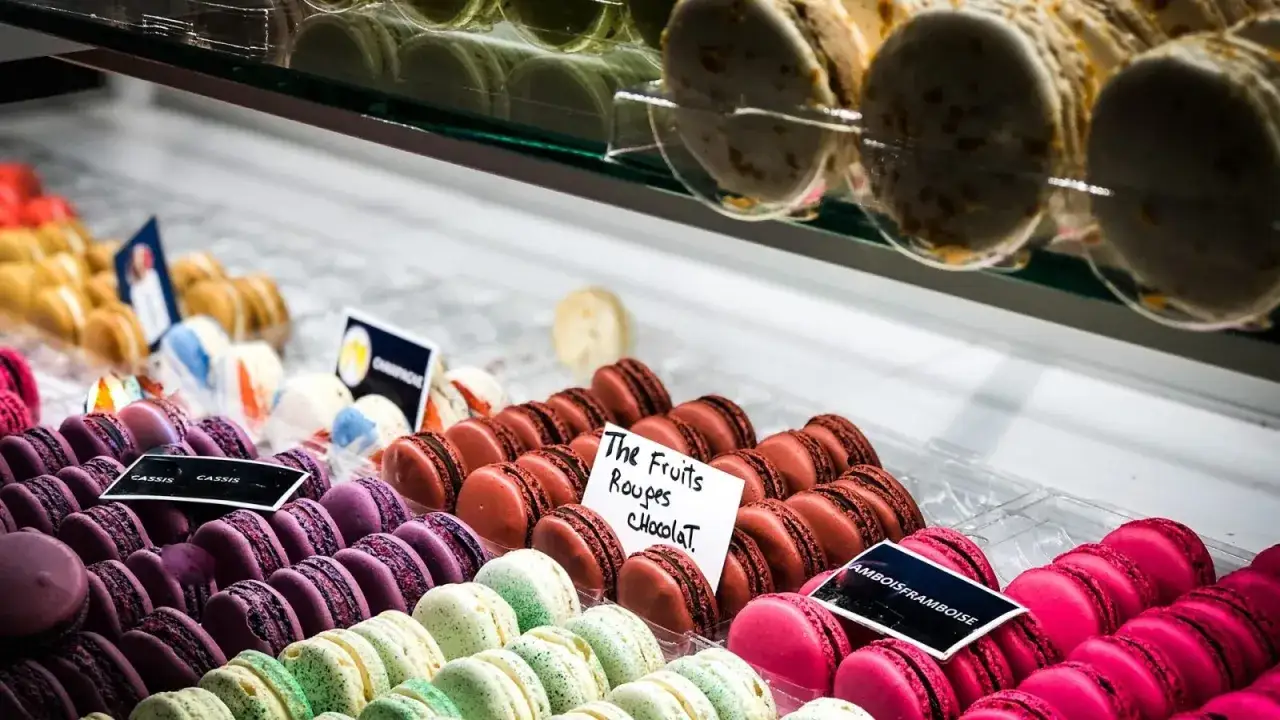 Kolorowe francuskie desery, makaroniki w odcieniach fioletu, zieleni, różu i brązu, kuszą smakiem.